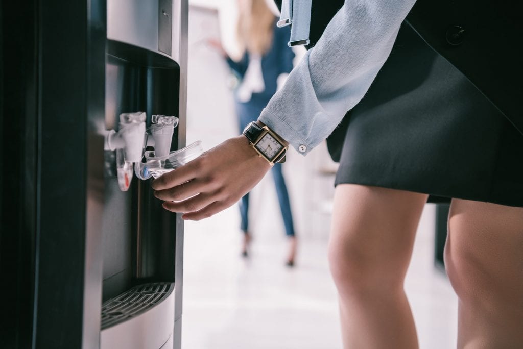 cropped shot of businesswoman pouring water from dispenser