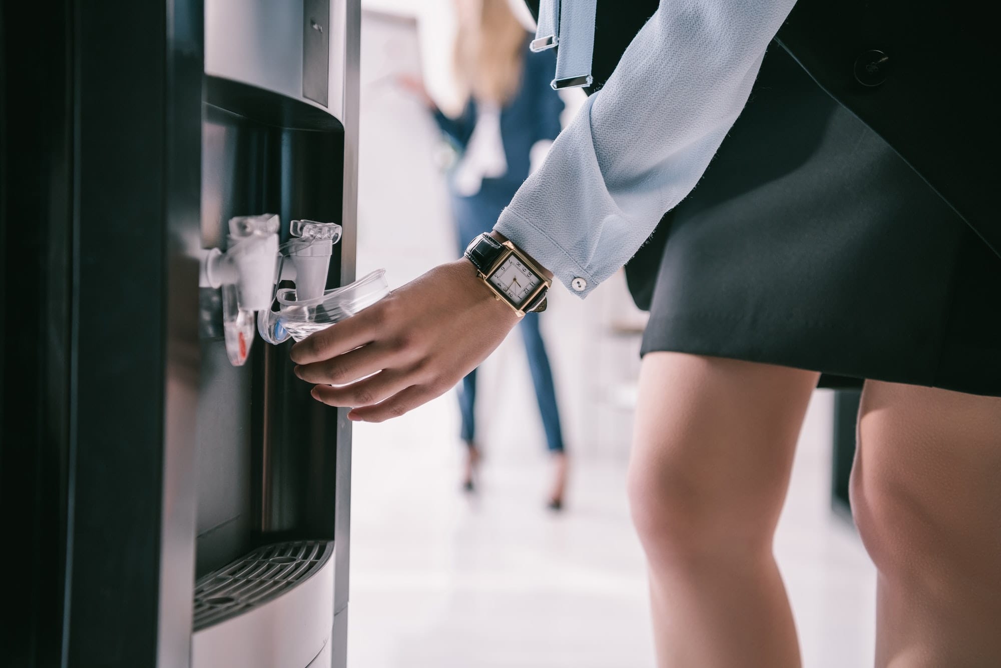 cropped shot of businesswoman pouring water from dispenser