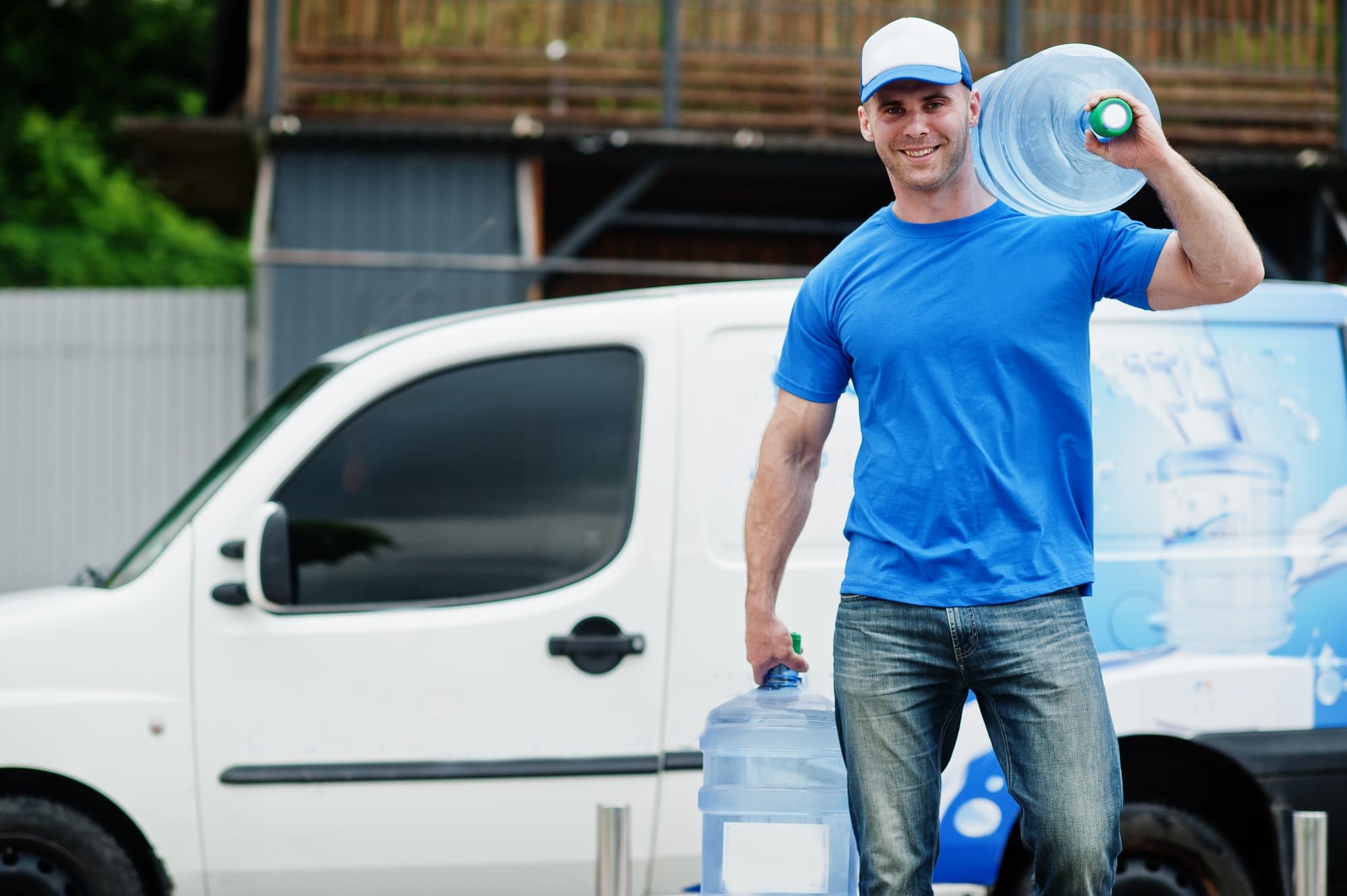 Delivery men in front cargo van delivering bottles of water.