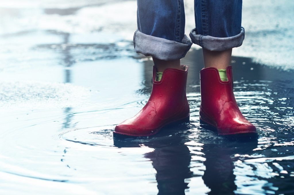 woman with red short boots standing in a puddle of rain water